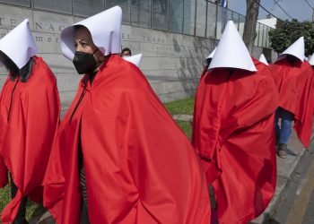 Manifestantes protestan ante Bachelet por la violencia contra las mujeres en Perú vistiendo trajes de «El cuento de la criada»